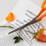 Tijeras naranjas cortando contrato de matrimonio y rosa naranja