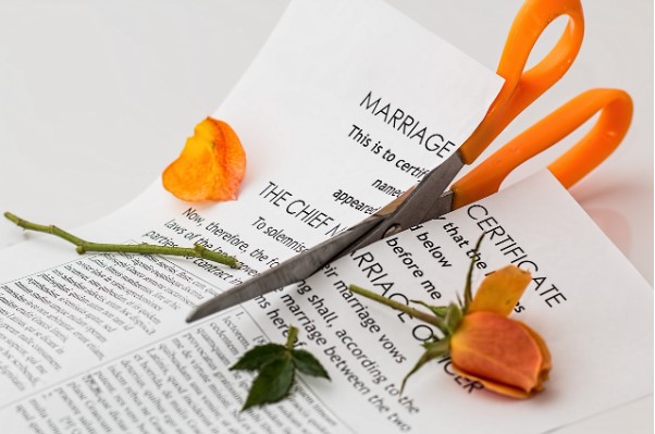 Tijeras naranjas cortando contrato de matrimonio y rosa naranja